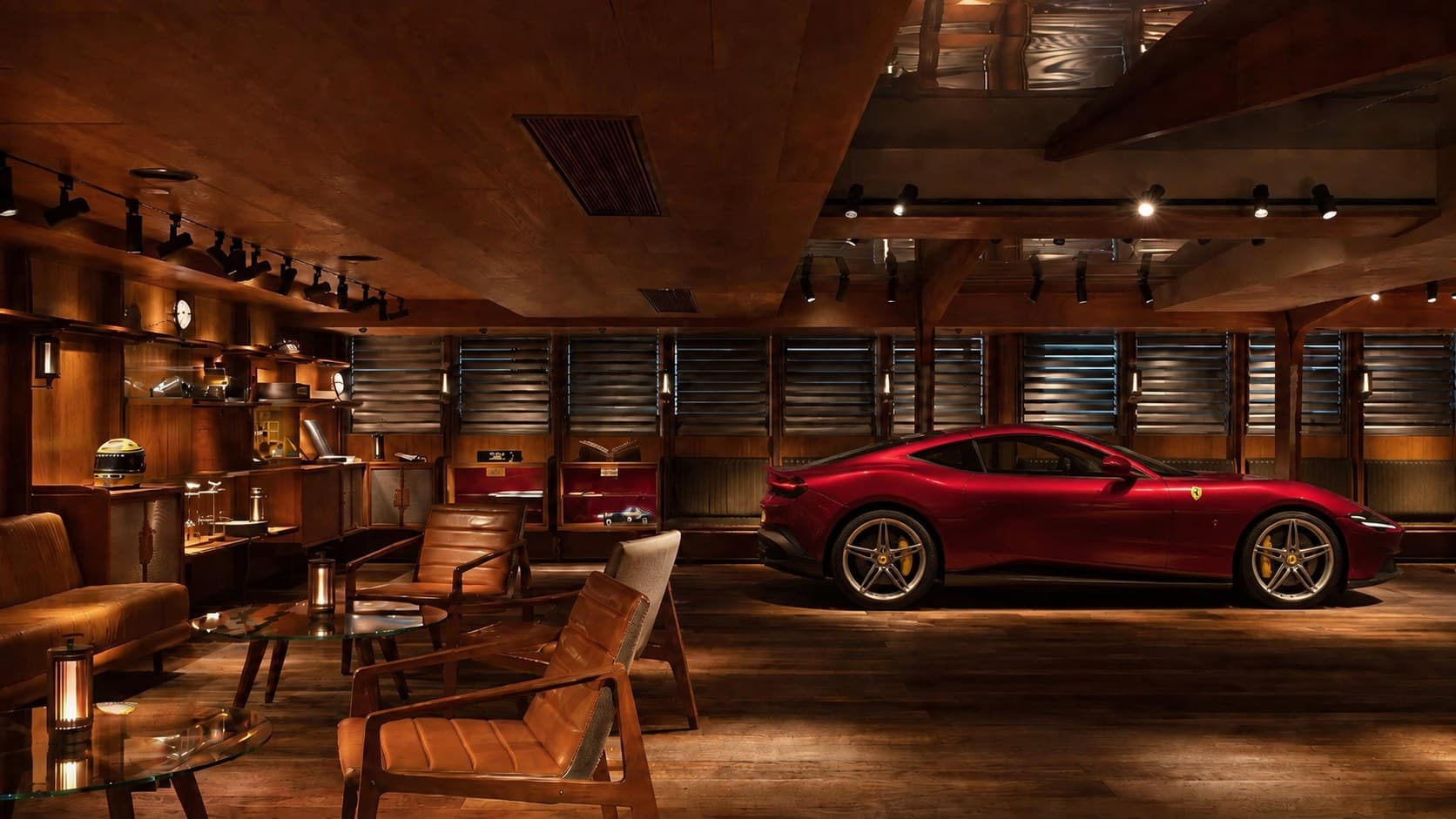 Interior do showroom Brasil Cars Premium — lounge com poltronas de couro, estante de memorabilia e uma Ferrari Roma vermelha ao fundo